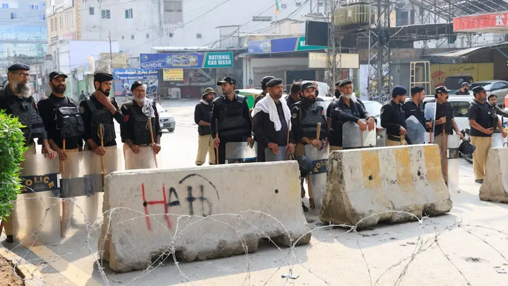पाकिस्तान के खैबर पख्तूनख्वा प्रांत के पेशावर में, पुलिसकर्मी रेड ज़ोन की ओर जाने वाली सड़क पर पहरा दे रहे हैं। (Image Credit - Reuters)